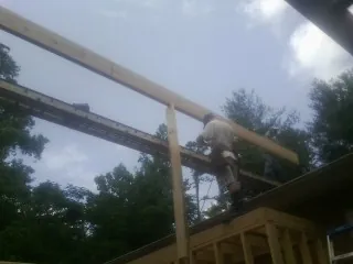 Carpenter setting a ridge beam over a new addition frame — Ice Dam Removal by Roofing Brothers in Marshfield
