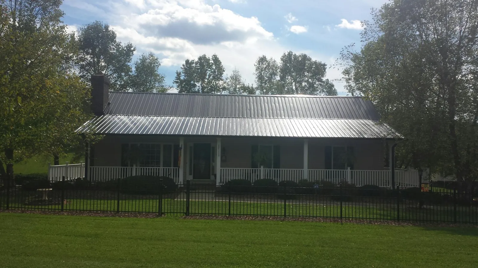 Gray metal roof on a brick ranch with a full width front porch — Gutter Guard Installation work by our crew in Marshfield