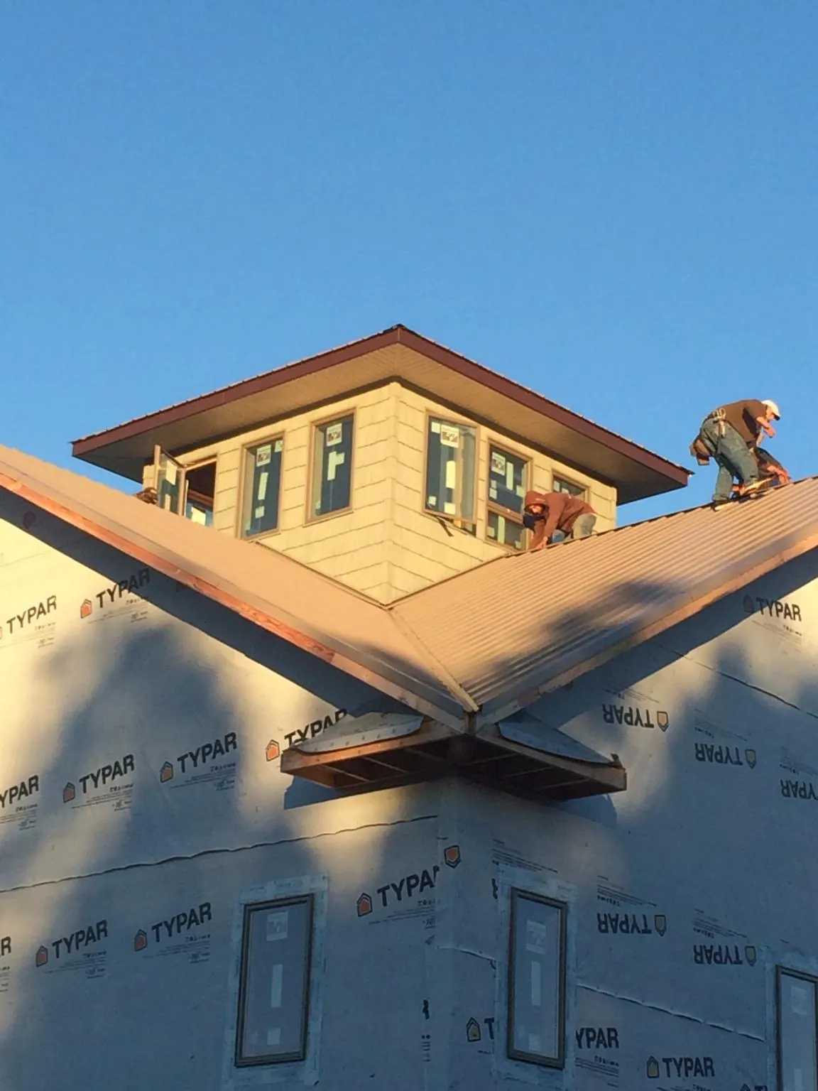Roofers working around a rooftop cupola on a new metal roof at sunset — Roof Waterproofing in Marshfield by Roofing Brothers
